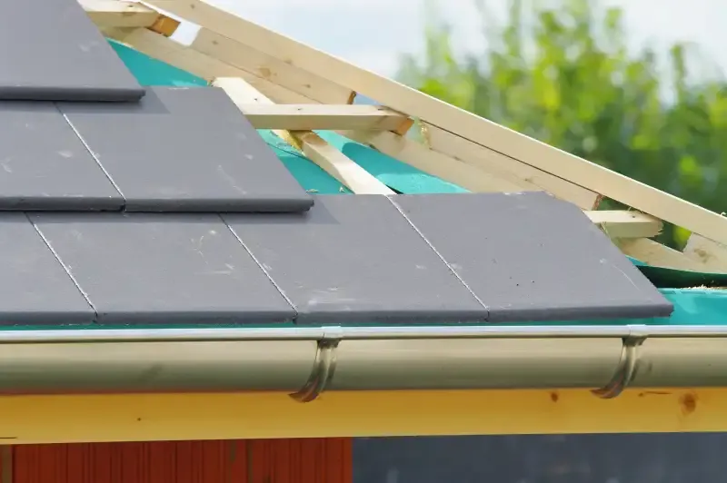 Toiture en ardoises avec gouttière, liteaux en bois et écran sous-toiture turquoise.