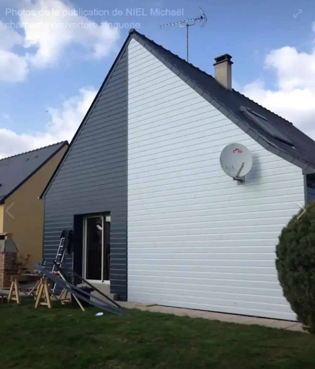 Façade d'une maison revêtue d'un bardage blanc et anthracite, avec une toiture sombre