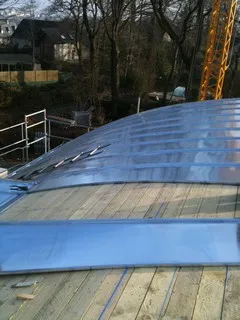 Toiture voûtée en zinc sur un chantier, avec un lattage en bois visible