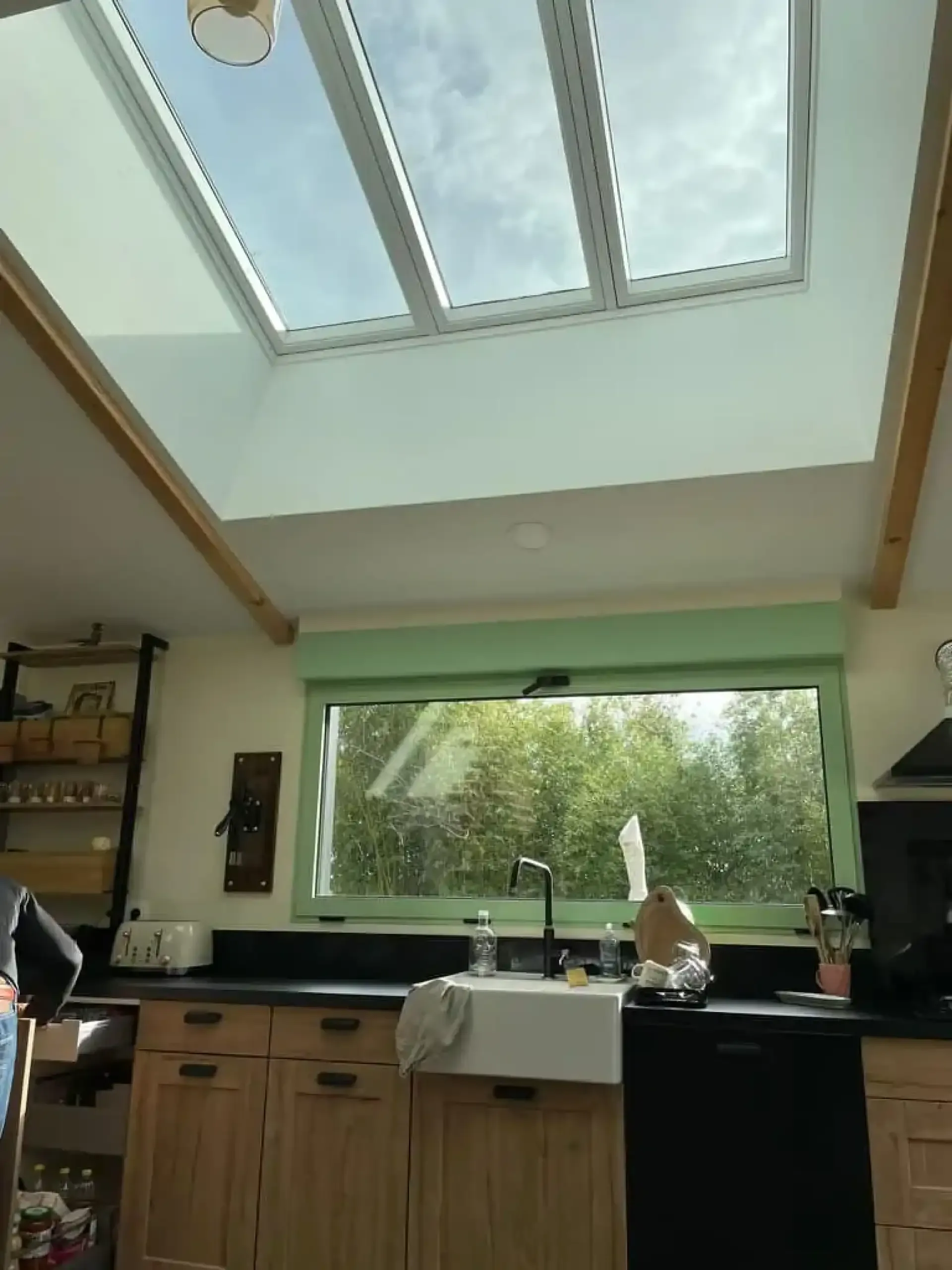 Verrière de toit à trois vantaux au-dessus d'une cuisine en bois, avec du ciel visible